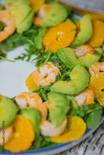 Green healthy vegan salad with arugula, avocado, shrimps and tangerines