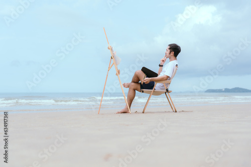 Hanumnang man relaxing by the sea in the morning sit and paint with watercolors as a hobby
