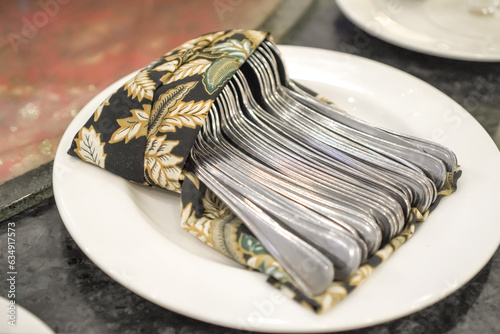 Many Silver Colored Tablespoon neatly arranged in a container. Group of clean spoon on white plate in hotel restauran wedding buffet. photo