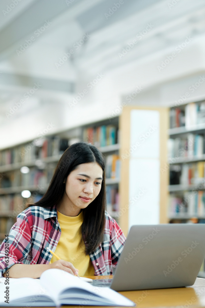 Young university student using laptop for online learning, searching and learning at library. Young university student using laptop for online learning, searching and learning at library.