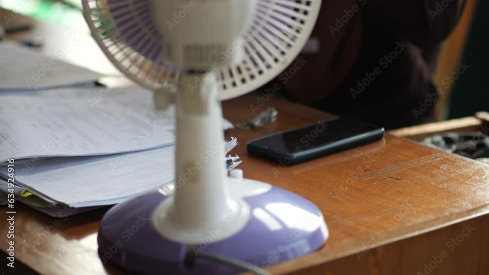 hand of an indonesian woman turns on a modern fan, adapting from the high temperatures at office. hand of an indonesian woman turns on a modern fan, adapting from the high temperatures at office.