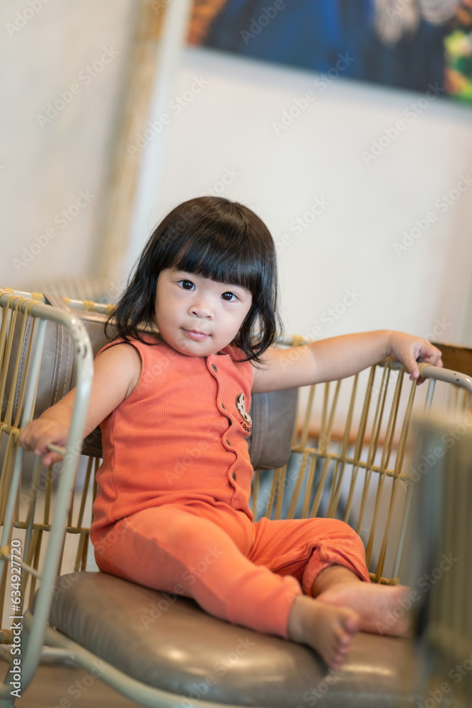 Portrait photo of white little girl with black hair is wearing orange suit in cutety action. People portrait photo with facing focus. Portrait photo of white little girl with black hair is wearing orange suit in cutety action. People portrait photo with facing focus.