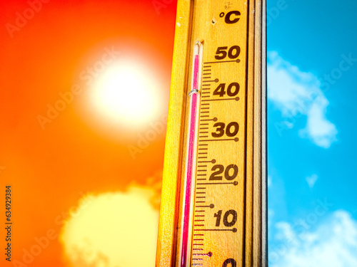 A hot summer day, with the thermometer showing a high heatwave temperature of 50 degrees Celsius. A red alarm gives a warning of the extreme weather conditions caused by global climate change.
