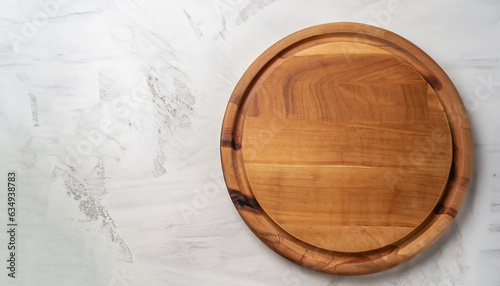 Empty wooden round board on white stone kitchen table, top view, flat lay. Wooden pizza platter, copy space.