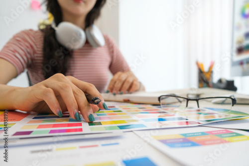 Interior designer working with color samples, choosing colorful paper charts at desk.