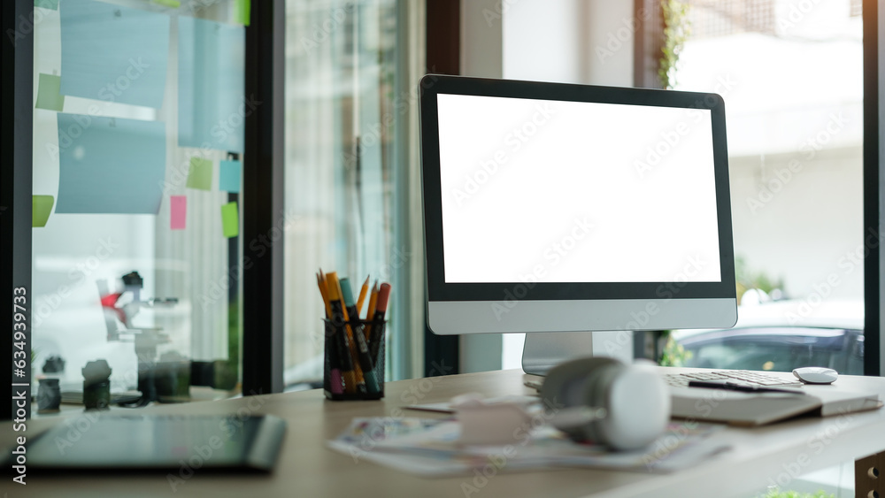 Blank computer monitor with headphone, graphic tablet and stationery on wooden table, creative workplace. Blank computer monitor with headphone, graphic tablet and stationery on wooden table, creative workplace.