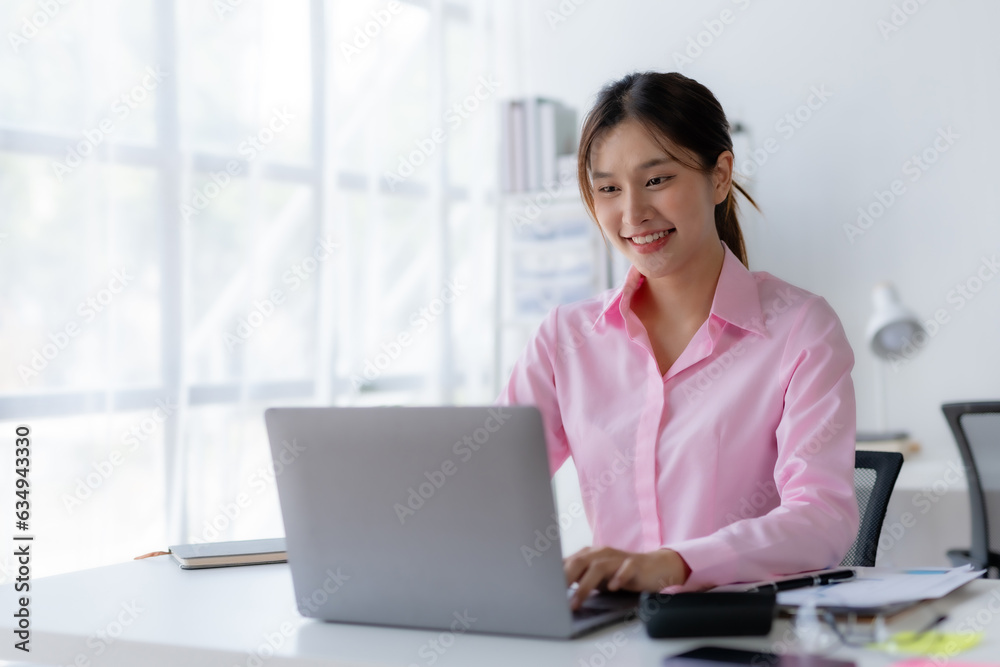 Successful Asian businesswoman smiling using laptop computer at office. Confident Asia businesswoman sitting happily in the office. Successful Asian businesswoman smiling using laptop computer at office. Confident Asia businesswoman sitting happily in the office.