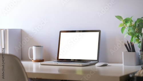Comfortable home office. Laptop computer, stationery and potted plant on white table. © wattana
