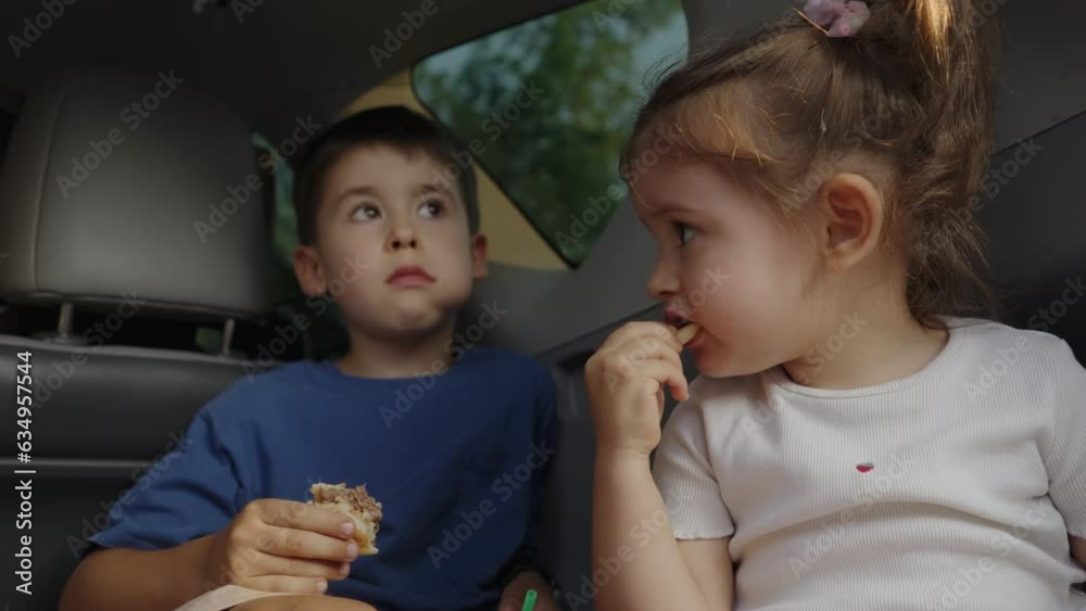 Two children are sitting in open trunk eating snacks, taking a break from the trip to catch up. Family auto vacation. Road trip. Two children are sitting in open trunk eating snacks, taking a break from the trip to catch up. Family auto vacation. Road trip.