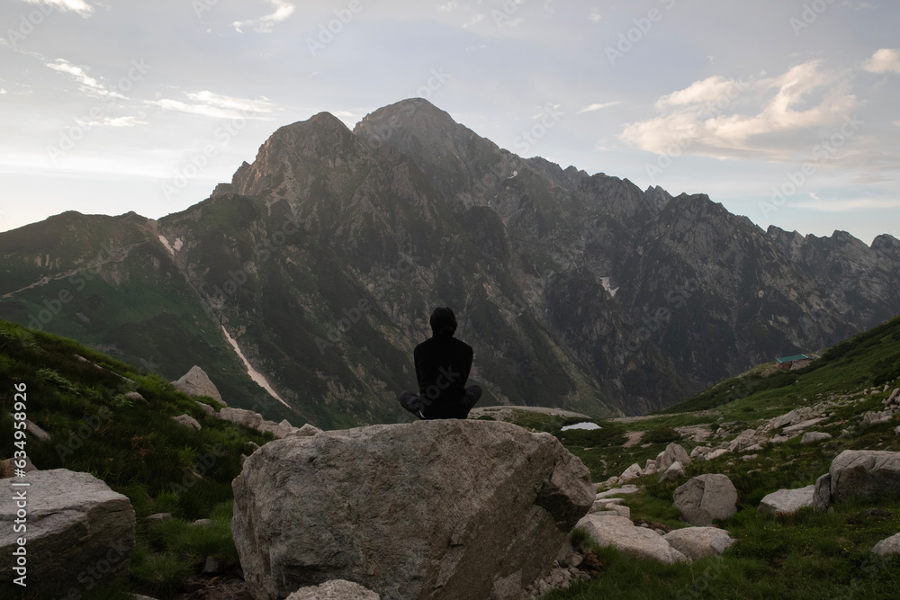 岩の上に座って剱岳を眺める男