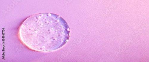 round transparent drop of clear gel serum on pink background