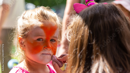 The face of a girl painted with colorful paints. Painting children's faces during a family picnic.