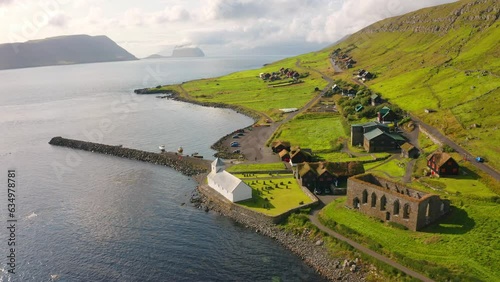 4k drone flight moving to the side footage (Ultra High Definition) of Kirkjubour village with Hestur Island on background. Bright morning scene of Faroe Islands, Denmark. Traveling concept background.