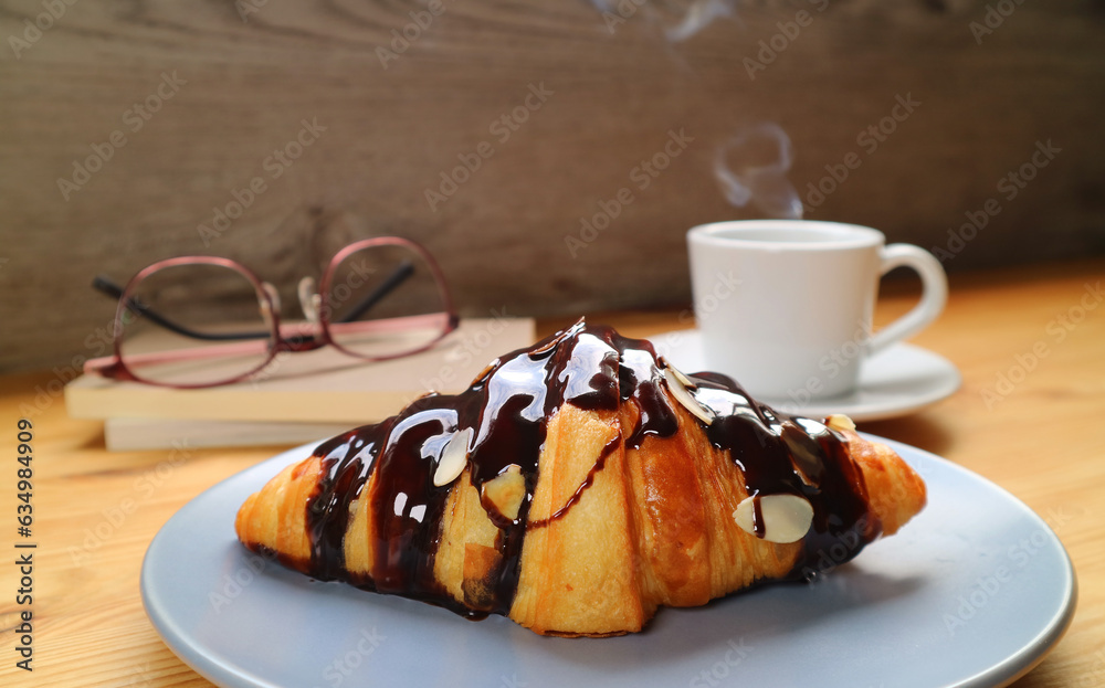 Mouthwatering Chocolate Croissant with a Cup of Steaming Coffee in the Backdrop Mouthwatering Chocolate Croissant with a Cup of Steaming Coffee in the Backdrop