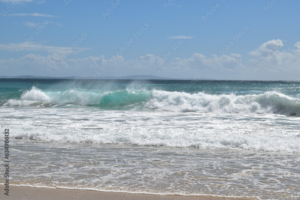 waves with spray and foam on a wide beach