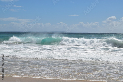 waves with spray and foam on a wide beach