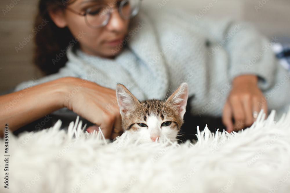 Beautiful woman dressed warm swetr and pijamas trousers playong with cat in the bed Beautiful woman dressed warm swetr and pijamas trousers playong with cat in the bed