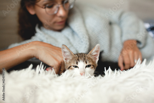 Beautiful woman dressed warm swetr and pijamas trousers playong with cat in the bed photo