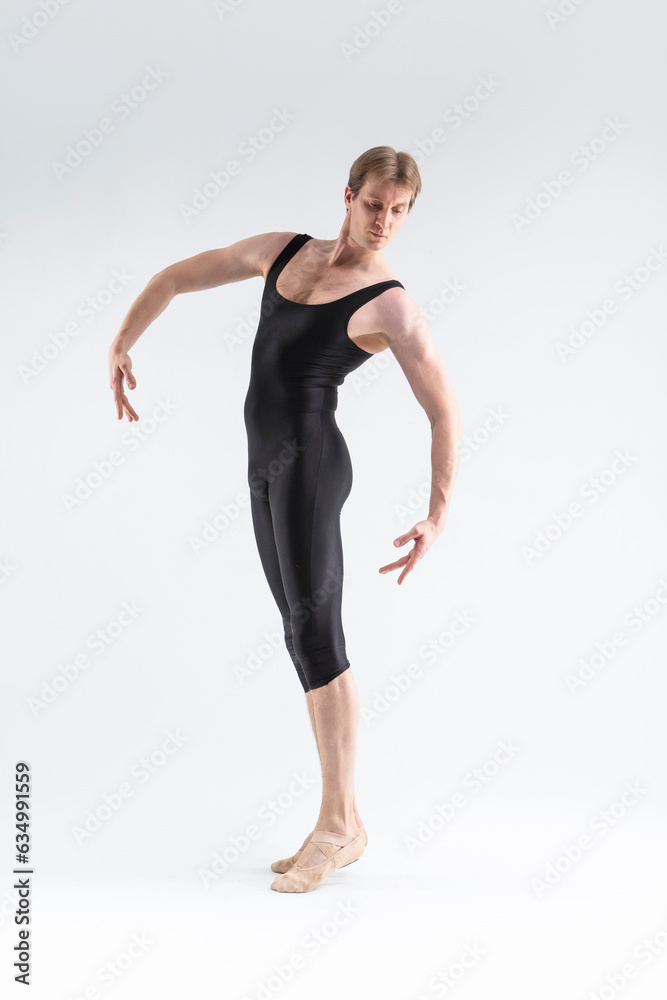 One Caucasian Ballet Dancer Young Athletic Man in Black Suit Posing in Studio On White.