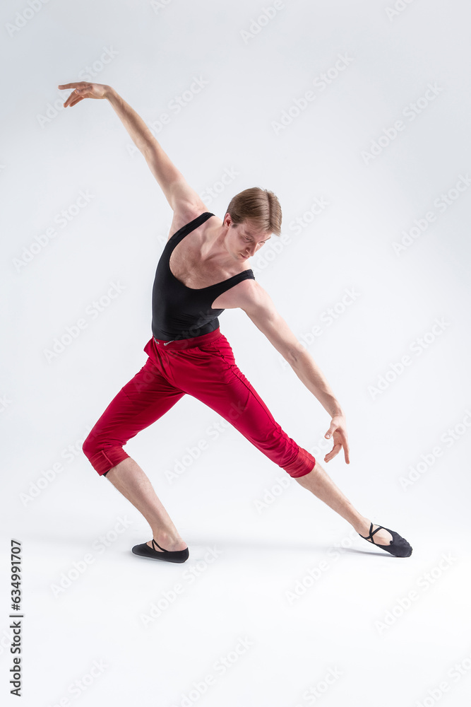 Fototapeta premium Concentrated Contemporary Ballet Dancer Flexible Athletic Man Posing in Red Tights in Ballanced Dance Pose With Hands Inclined In Line on White