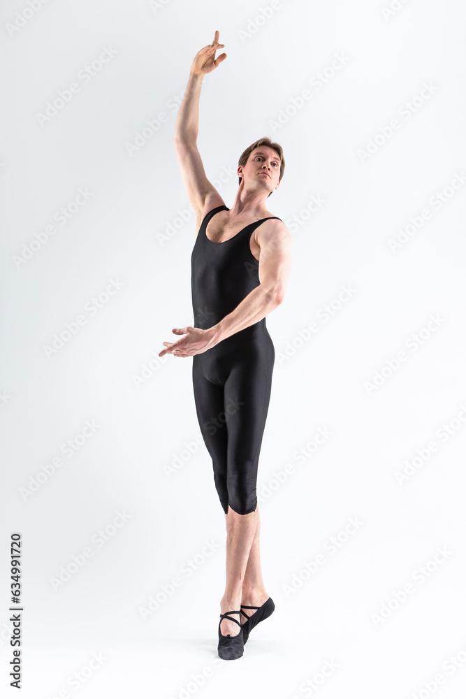 Sportive Caucasian Male Ballet Dancer Flexible Athletic Man Posing in Black Tights in Ballanced Dance Pose With Hands Lifted.