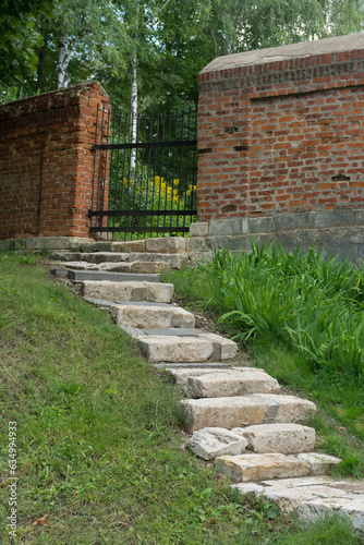 brick wall and stone steps leading to a metal gate