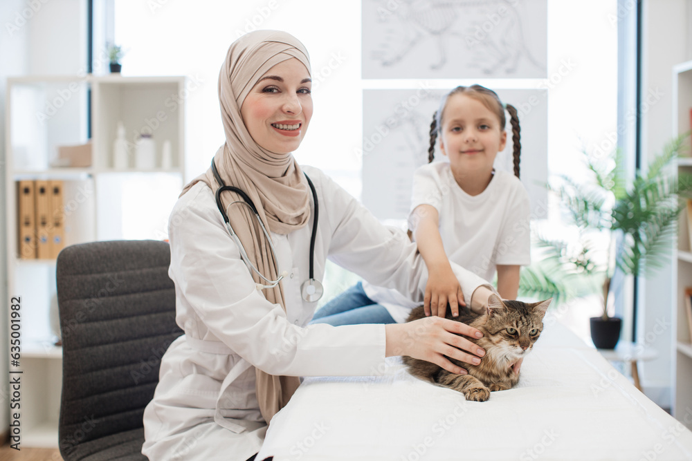 Arabian vet doctor and girl posing on camera with furry cat