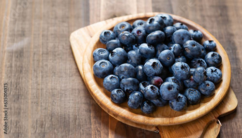 Blueberries on a board over wooden table.