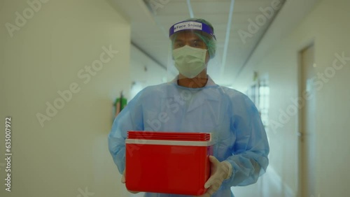Asian medical staff with PPE suit carring specimens in red biohazard box, Disease Control and Prevention. photo
