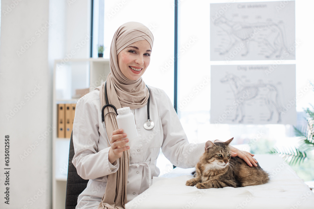Arabian vet posing with cat and bottle of pills in exam room