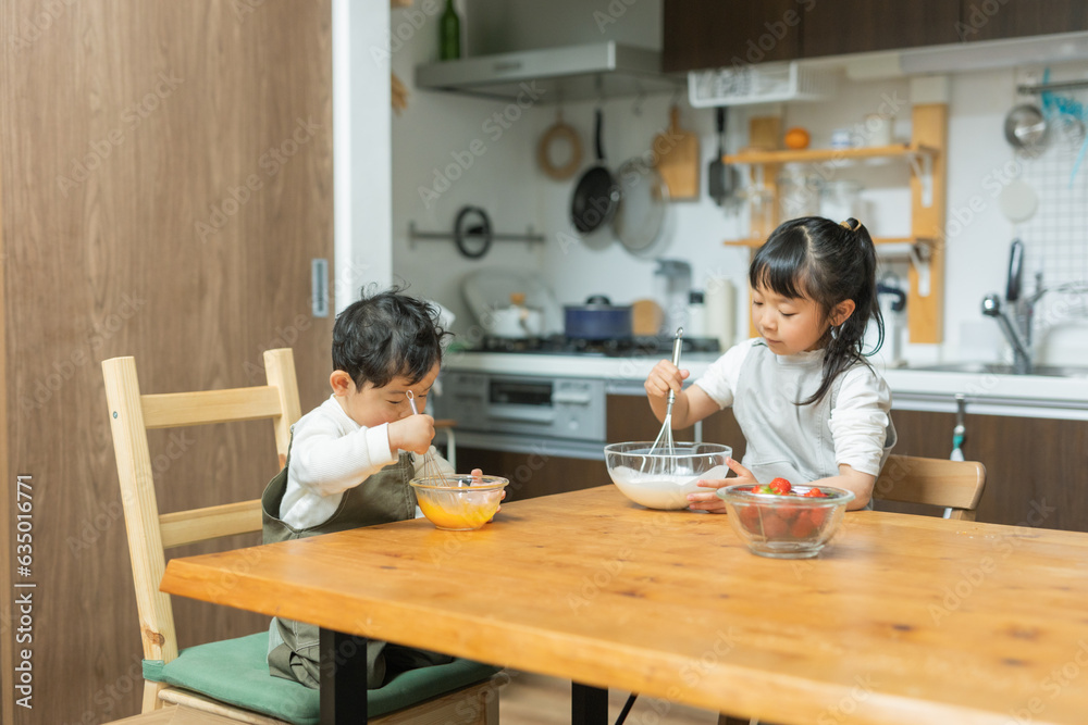 春の昼間のキッチンで二人で仲良くお菓子作りの手伝いをする日本人の幼い兄弟 春の昼間のキッチンで二人で仲良くお菓子作りの手伝いをする日本人の幼い兄弟