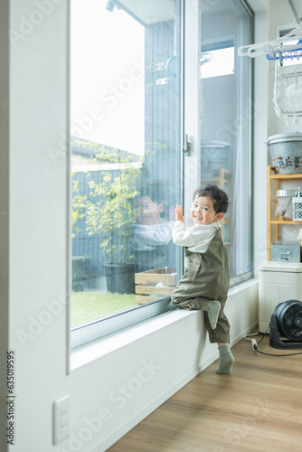 春の日中の明るい部屋の窓際によじ登り笑顔で正面を向く日本人の子ども © 宏員 武井
