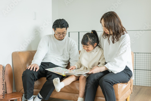 秋の昼過ぎ、家で座って楽しそうに本を読む日本人の子供とその家族