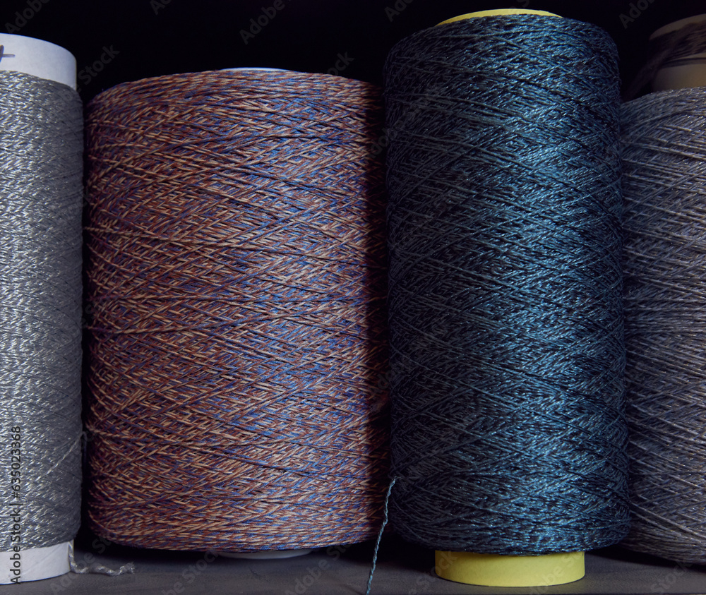 Raw spindles of industrial cotton on a weaving factory shelf, hand