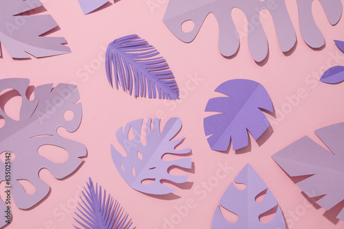 Paper purple tropical leaves on a pink background.