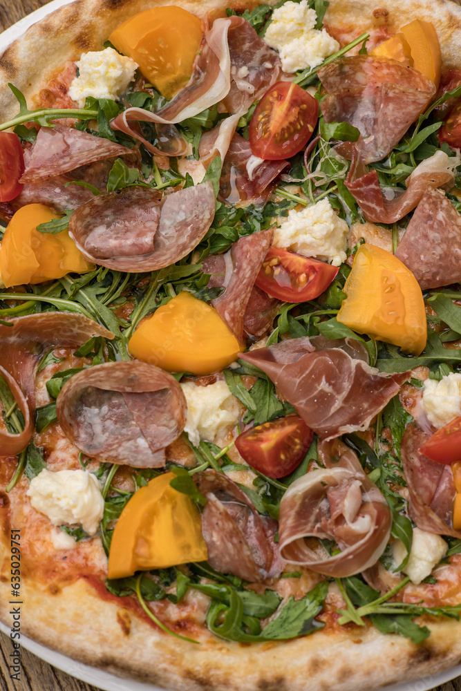 Delicious pizza with meat and yellow tomatoes 