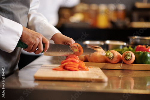 Chef slicing tomatoes with sharp knife when cooking salad