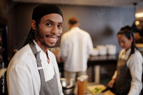 Portrait of smiling sous-chef enjoying working in kitchen of popular hotel