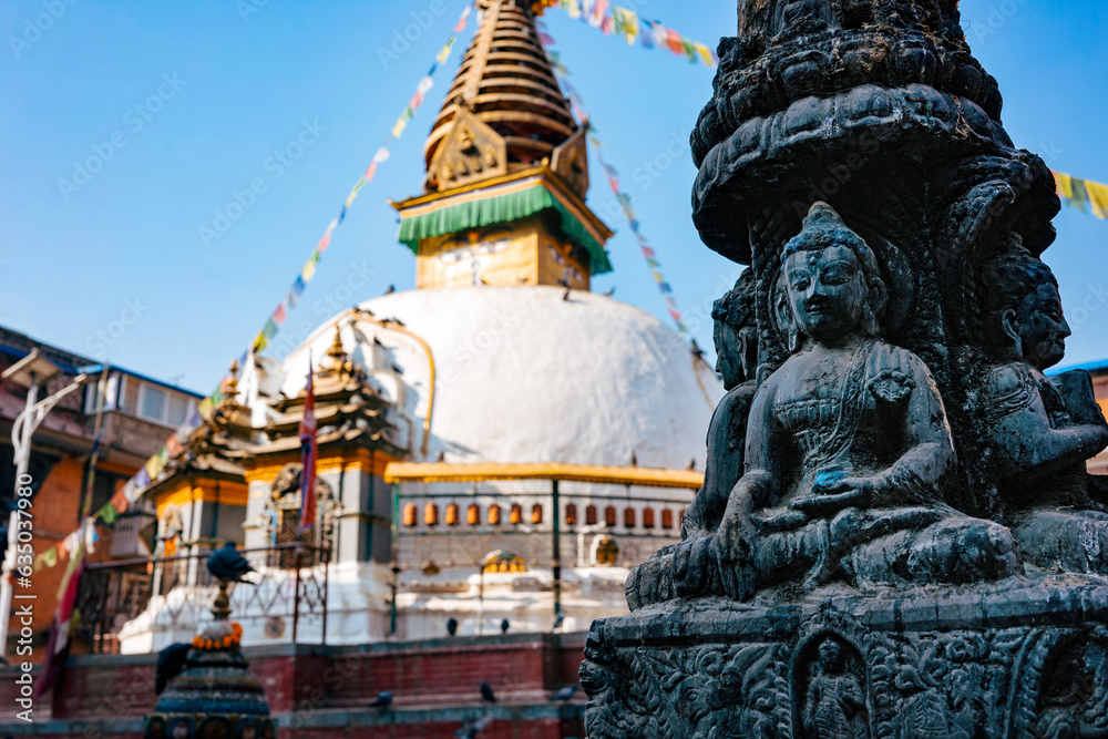 Fototapeta premium A golden-topped Buddhist stupa with colorful prayer flags in the old town of Kathmandu Nepal. A religious place.