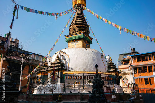 A golden-topped Buddhist stupa with colorful prayer flags in the old town of Kathmandu Nepal. A religious place.