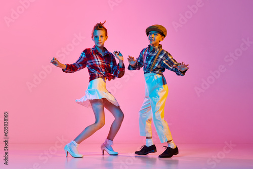 Photography Beautiful children, boy and girl in stylish retro clothes dancing against pink studio background in neon light