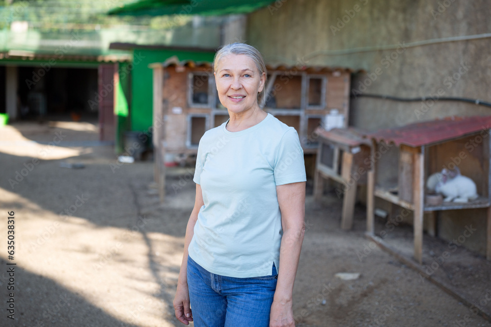 A woman stands in front of cages with rabbits.
