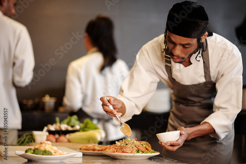 Fotografija Serious cook pouring thousand island dressing over salad