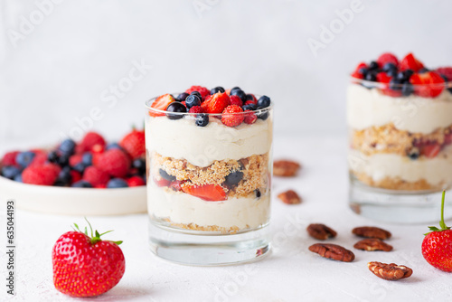 Sweet dessert in a glasses with berries, nuts, whipped cream and biscuit. Healthy food, sugar, gluten and lactose free.