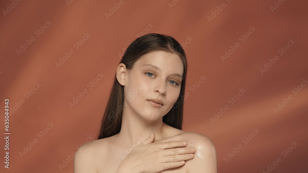 A young woman enjoys her smooth clean silky skin by touching it. Portrait of a seminude woman in the studio on a red background close up. The concept of beauty, cosmetology, skin care. A young woman enjoys her smooth clean silky skin by touching it. Portrait of a seminude woman in the studio on a red background close up. The concept of beauty, cosmetology, skin care.