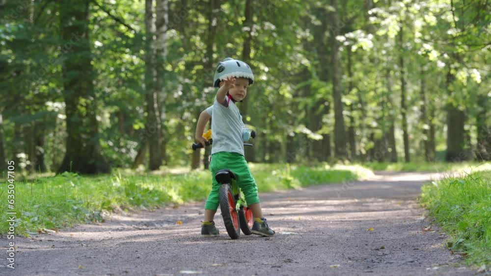 toddler child in protective helmet riding balance bike in summer park toddler child in protective helmet riding balance bike in summer park