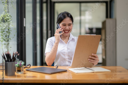 Female employee talking on the phone while checking documents. Call to verify the authenticity of the document.