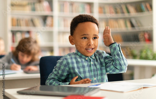 Smart black boy raising his hand to answer a question during lesson in elementary school  kid engaging in the lesson