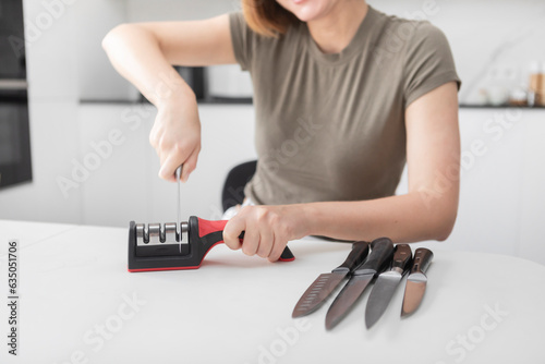 Close-up of woman sharpening knife with special knife sharpener at home 