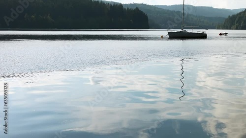 Mountain lake in summer, boat at anchor, man diving into the water photo